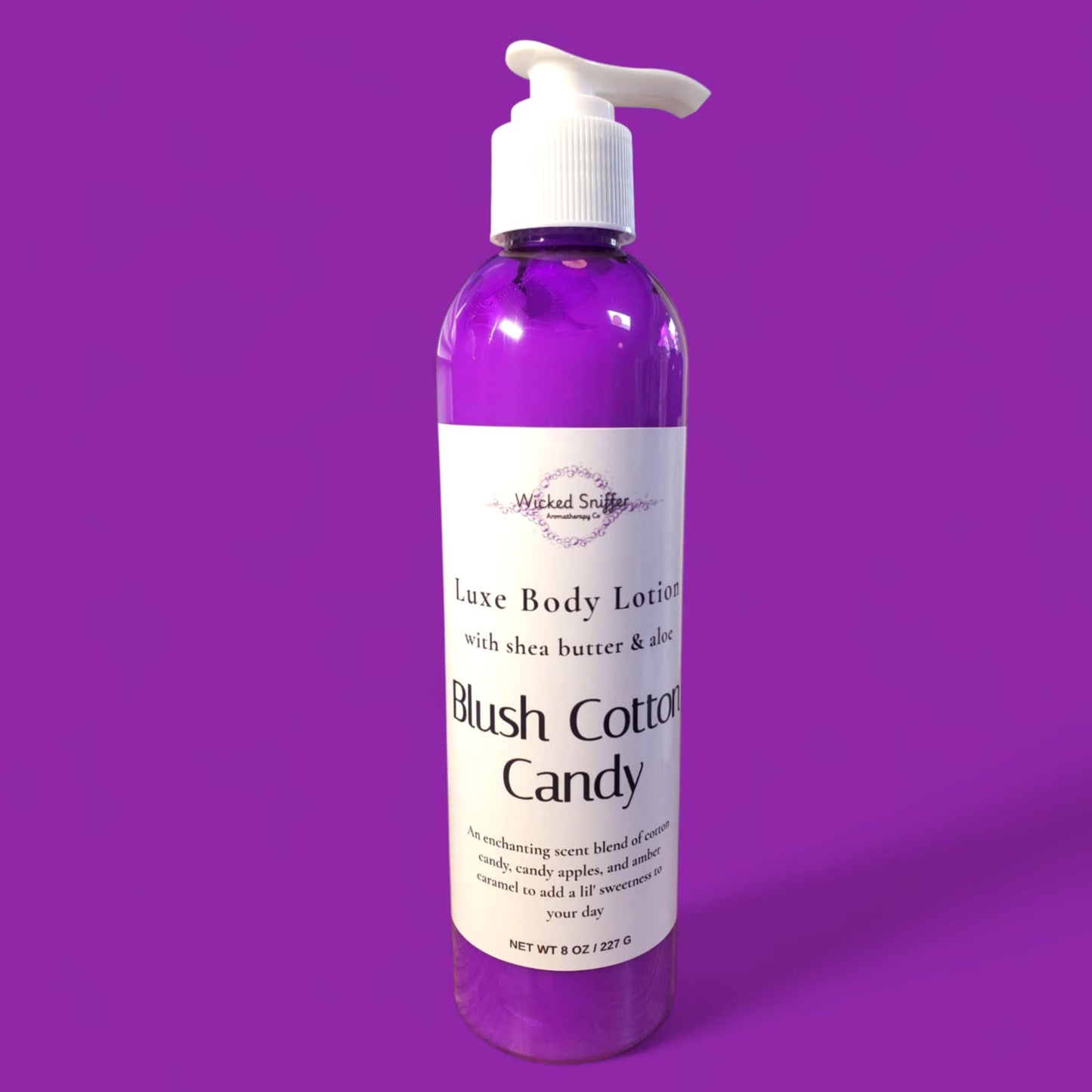Bottle of 'Blush Cotton Candy' body lotion on a purple background