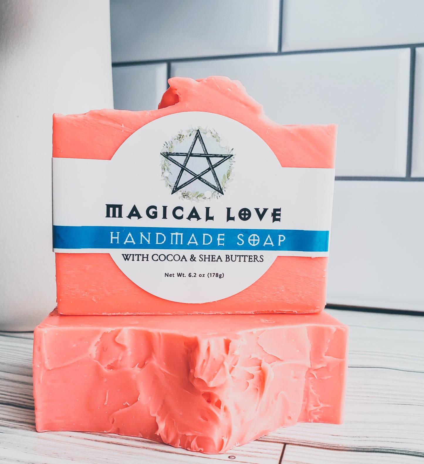 Photo of two bright orange soaps with a white label with a blue stripe and a pentagram. 