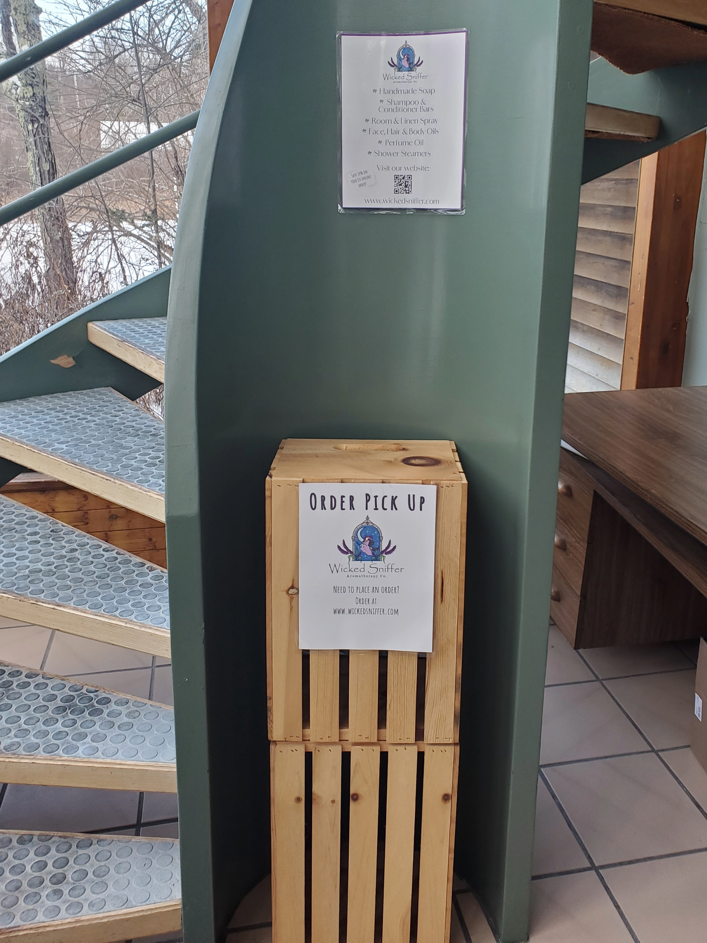 Wooden box with an order pick up sign attached to a green metal structure.