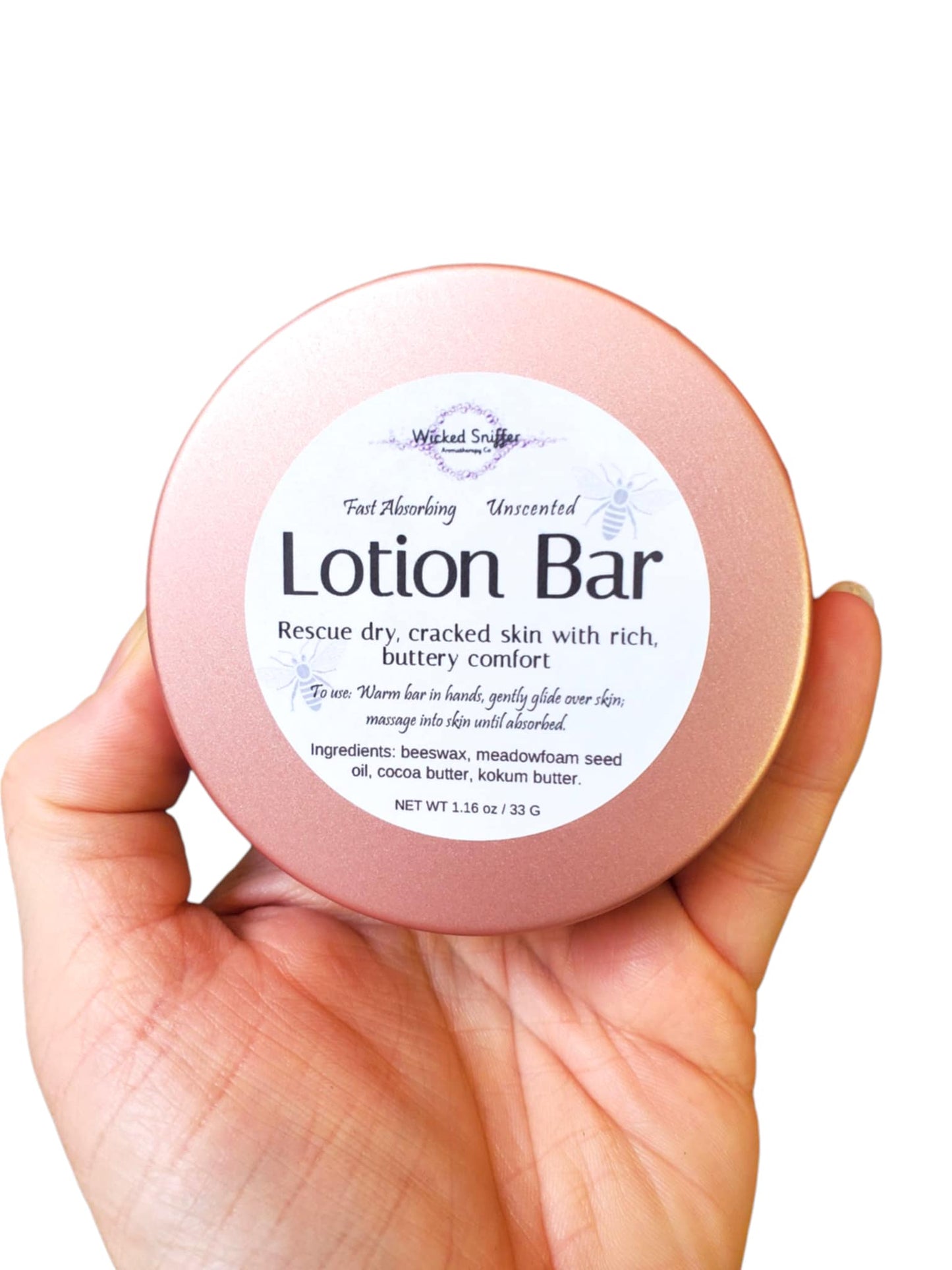 Hand holding a pink lotion bar tin with a white label on a white background