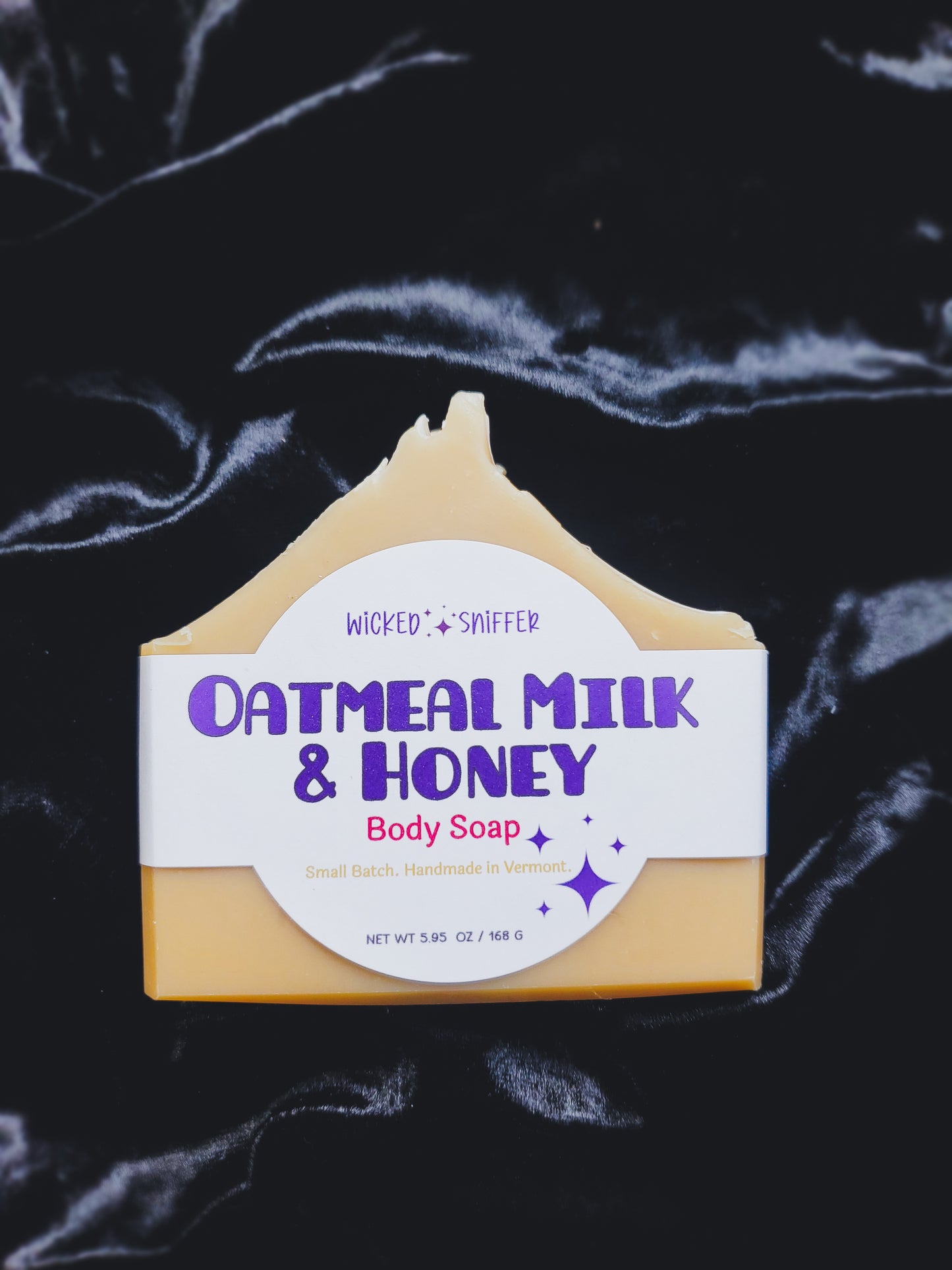 Bar of oatmeal milk and honey body soap with a white label on a dark background
