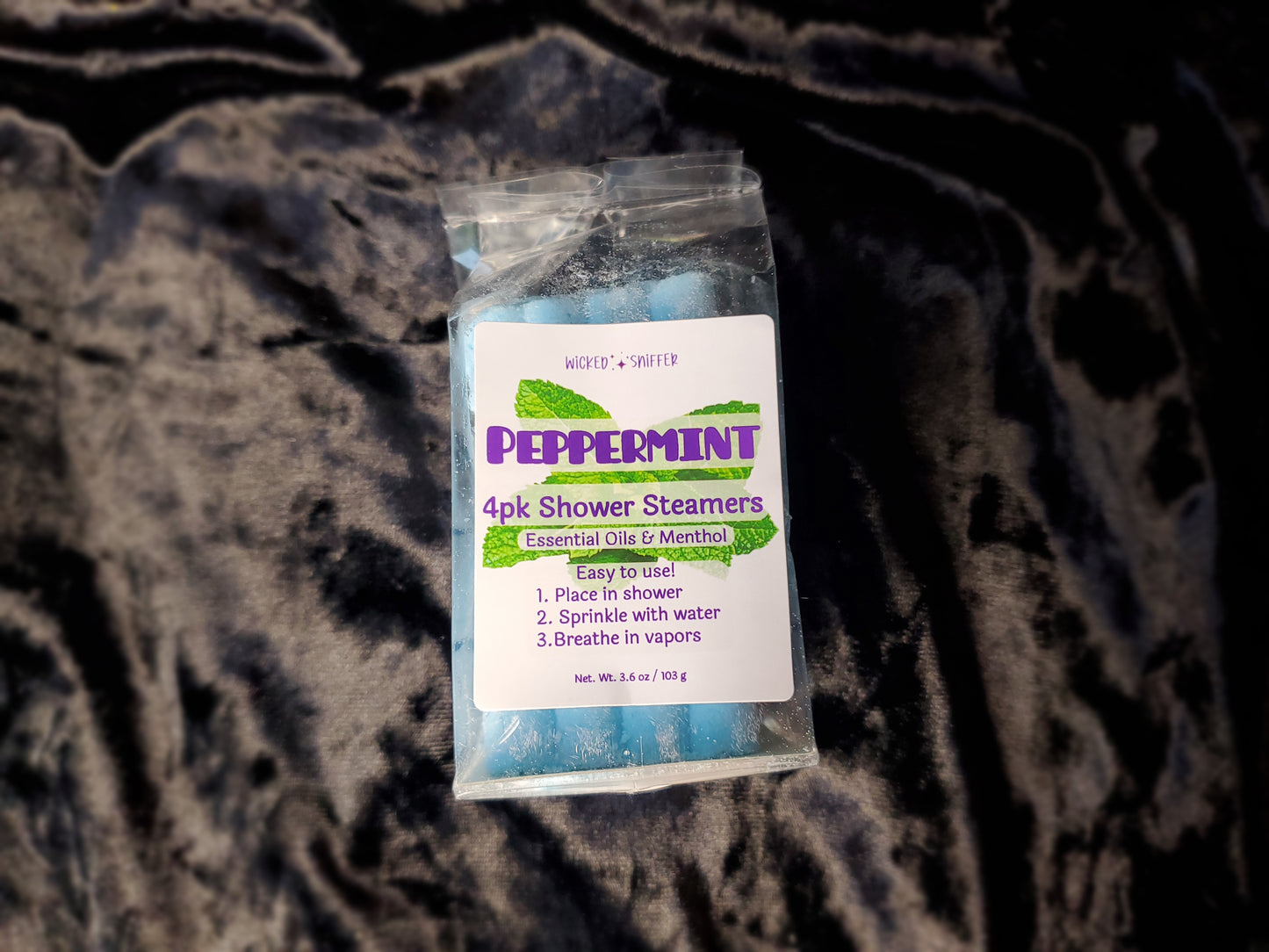 Pack of peppermint shower steamers on a textured dark surface