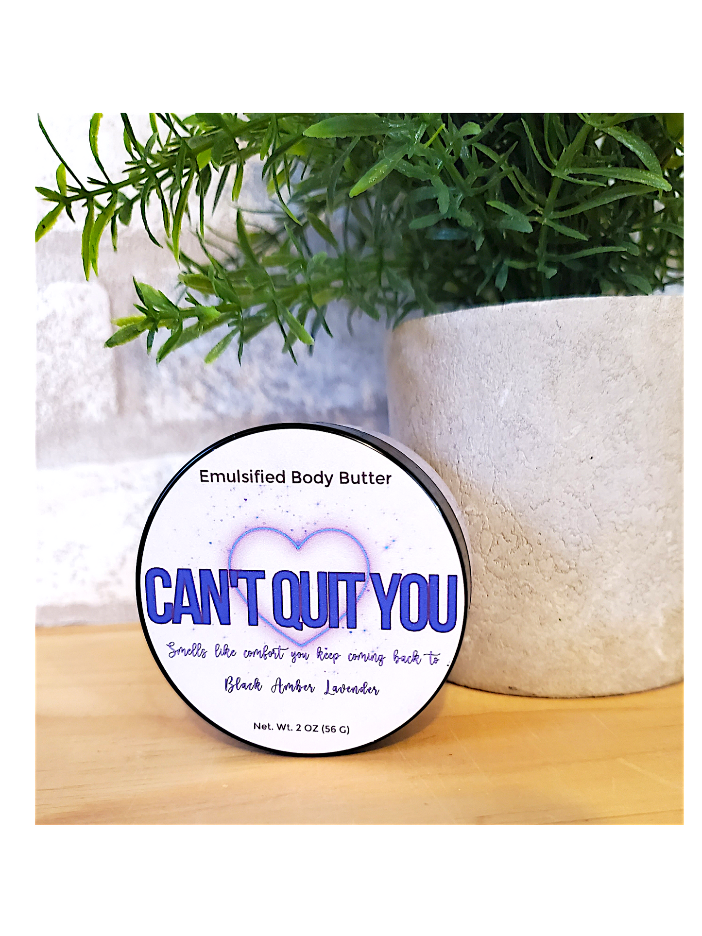 Emulsified body butter container labeled 'Can't Quit You' with greenery in the background