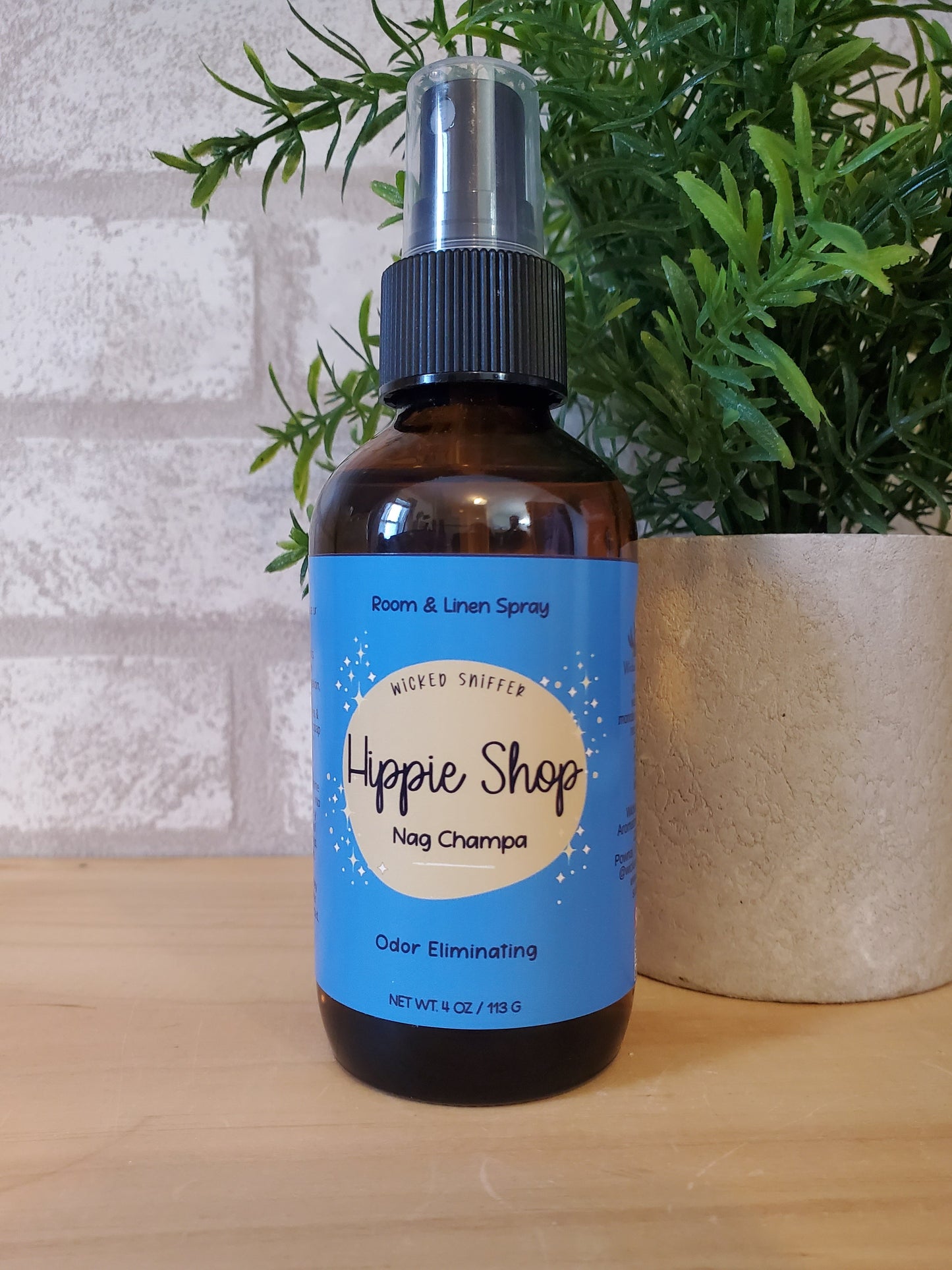 Bottle of 'Happy Shop' room spray with a blue label on a wooden surface.