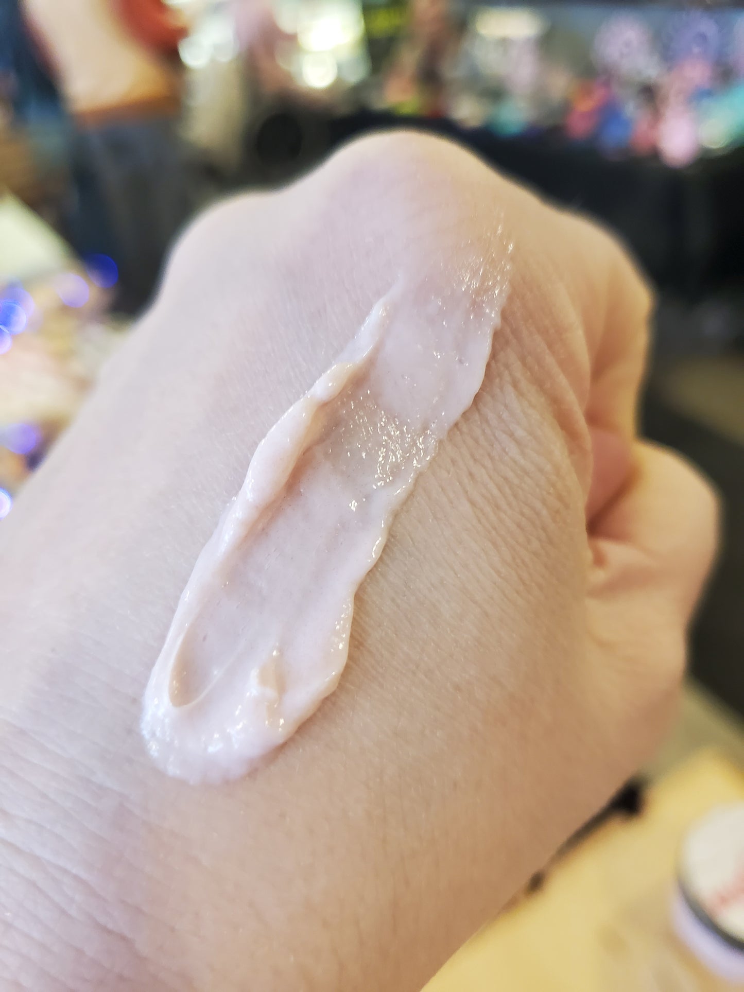 Hand applying a cream substance on skin with a blurred background