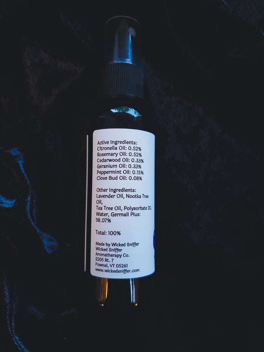 A black spray bottle with a white label showing active ingredients, photographed against a dark textured background.