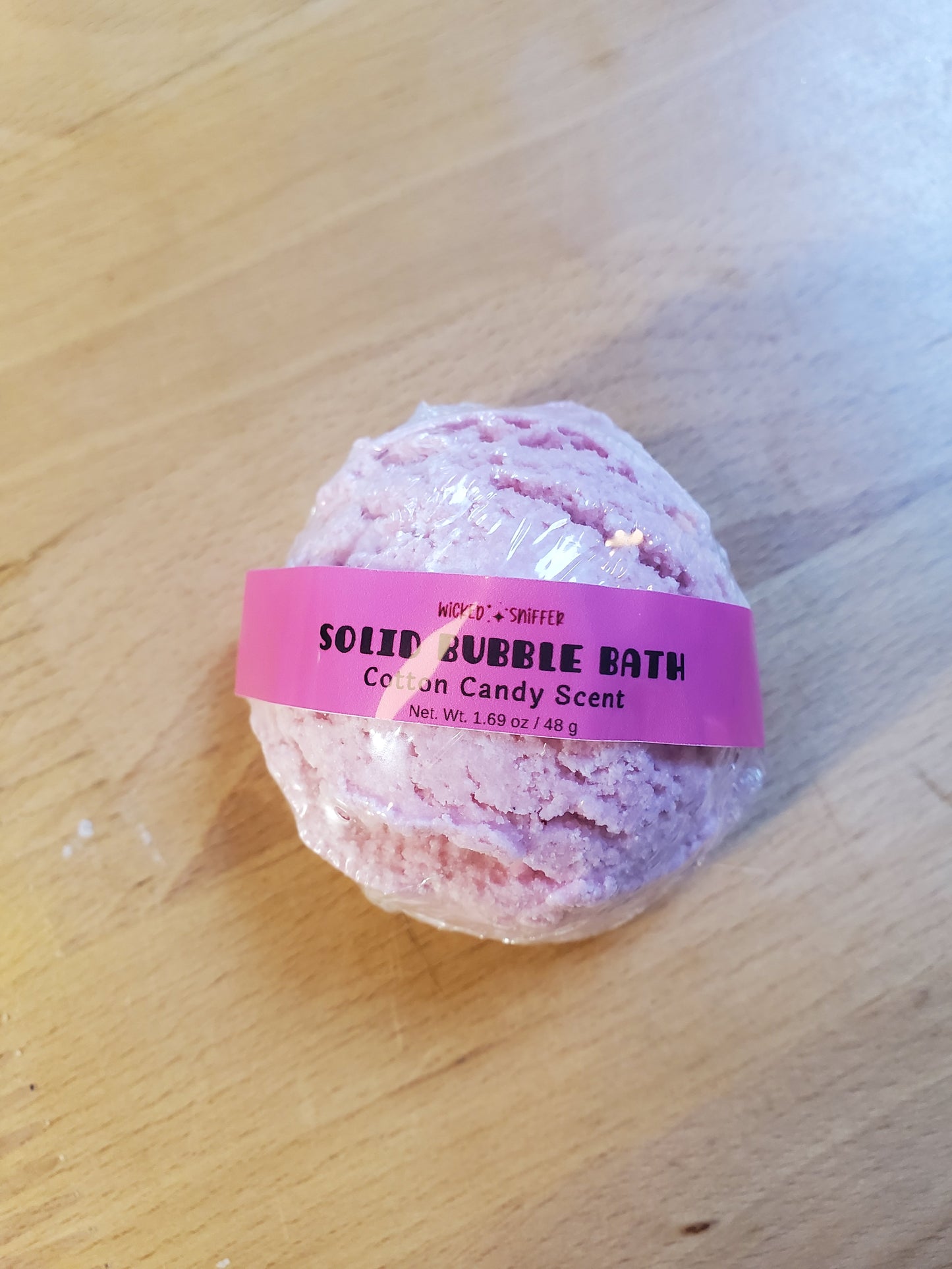 Pink bubble scoop with a pink band on a wooden surface
