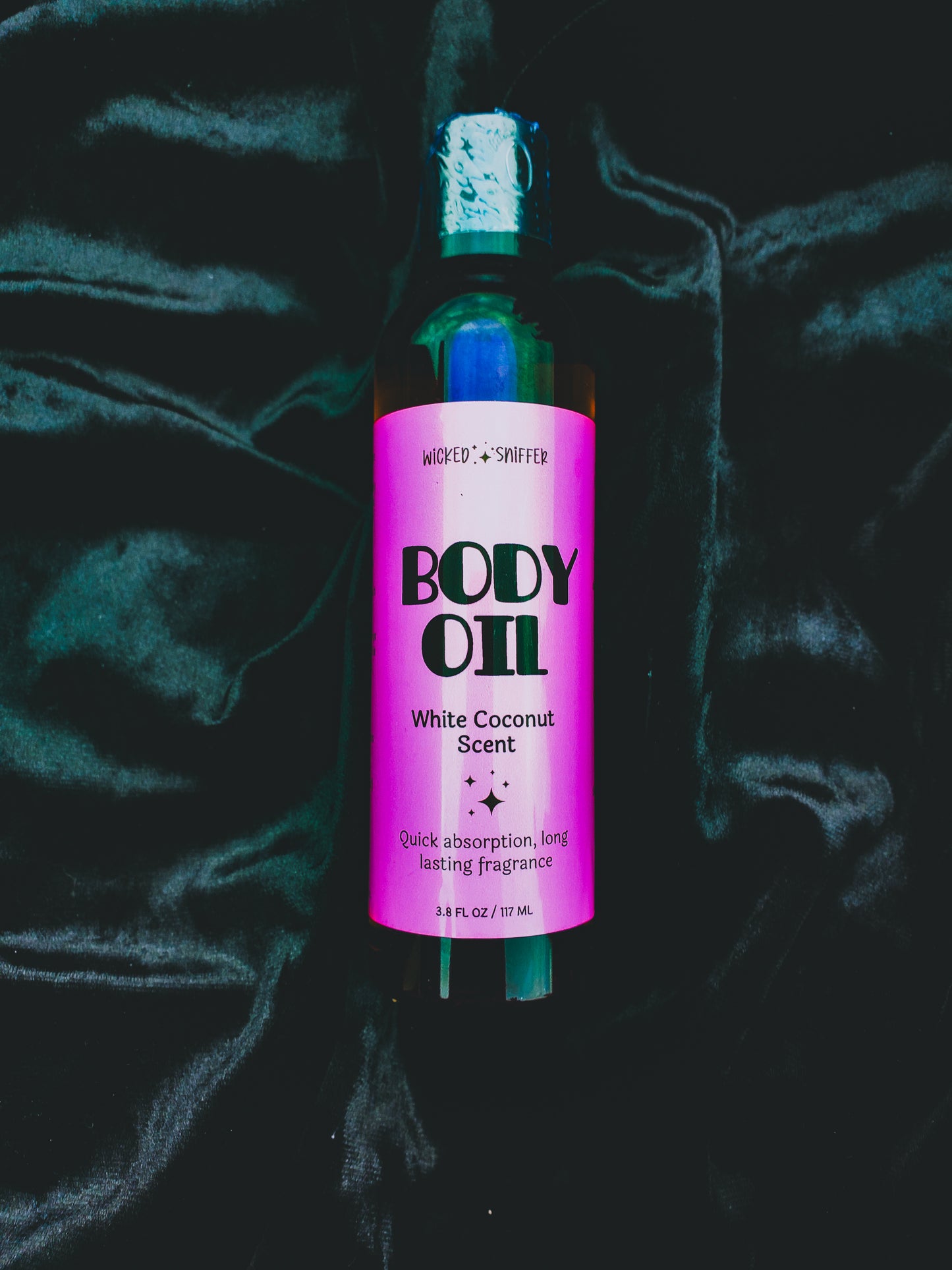 Bottle of body oil with a pink label on a dark textured background