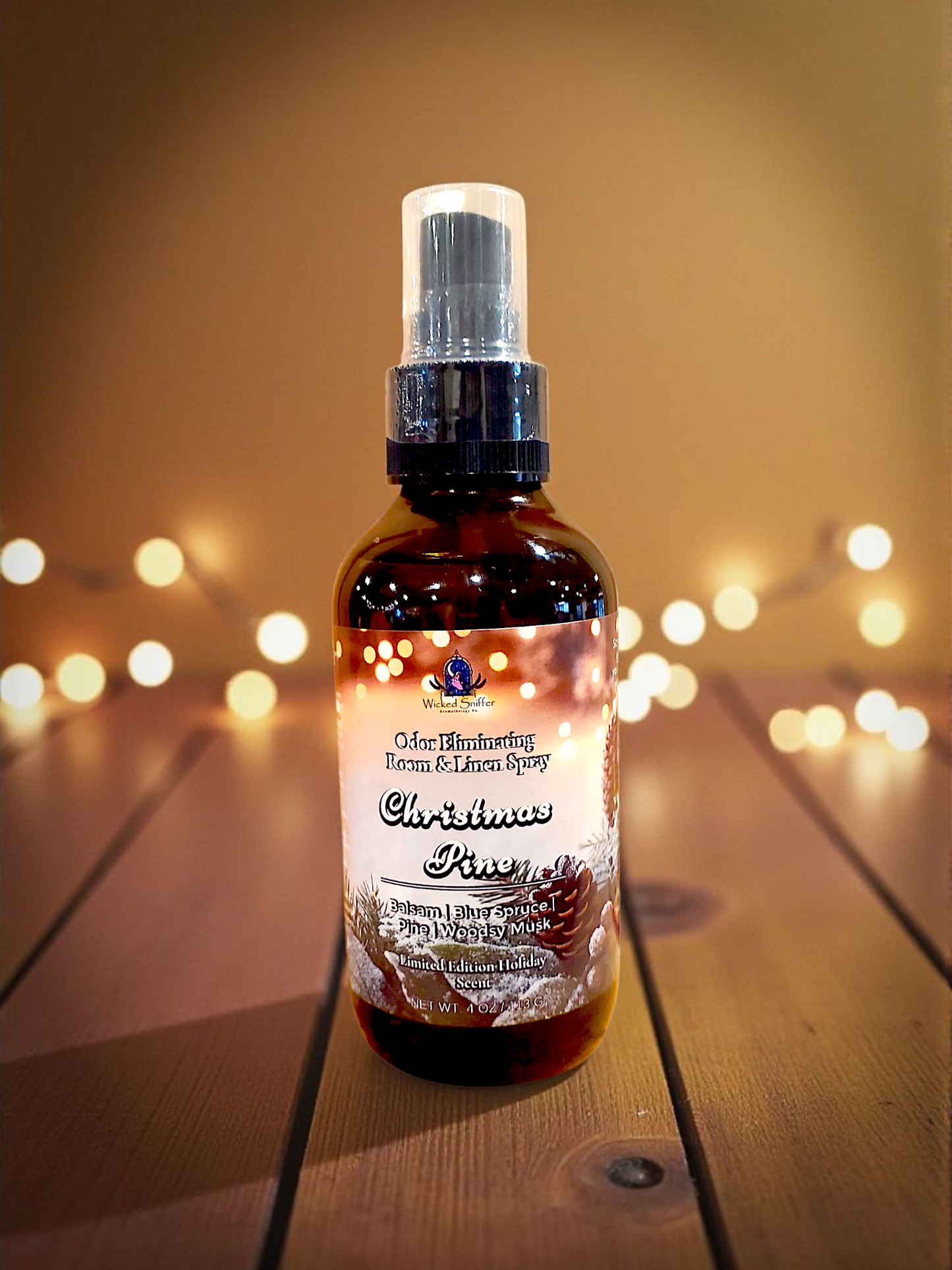 Bottle of Christmas Pine room spray on a wooden surface with blurred lights in the background