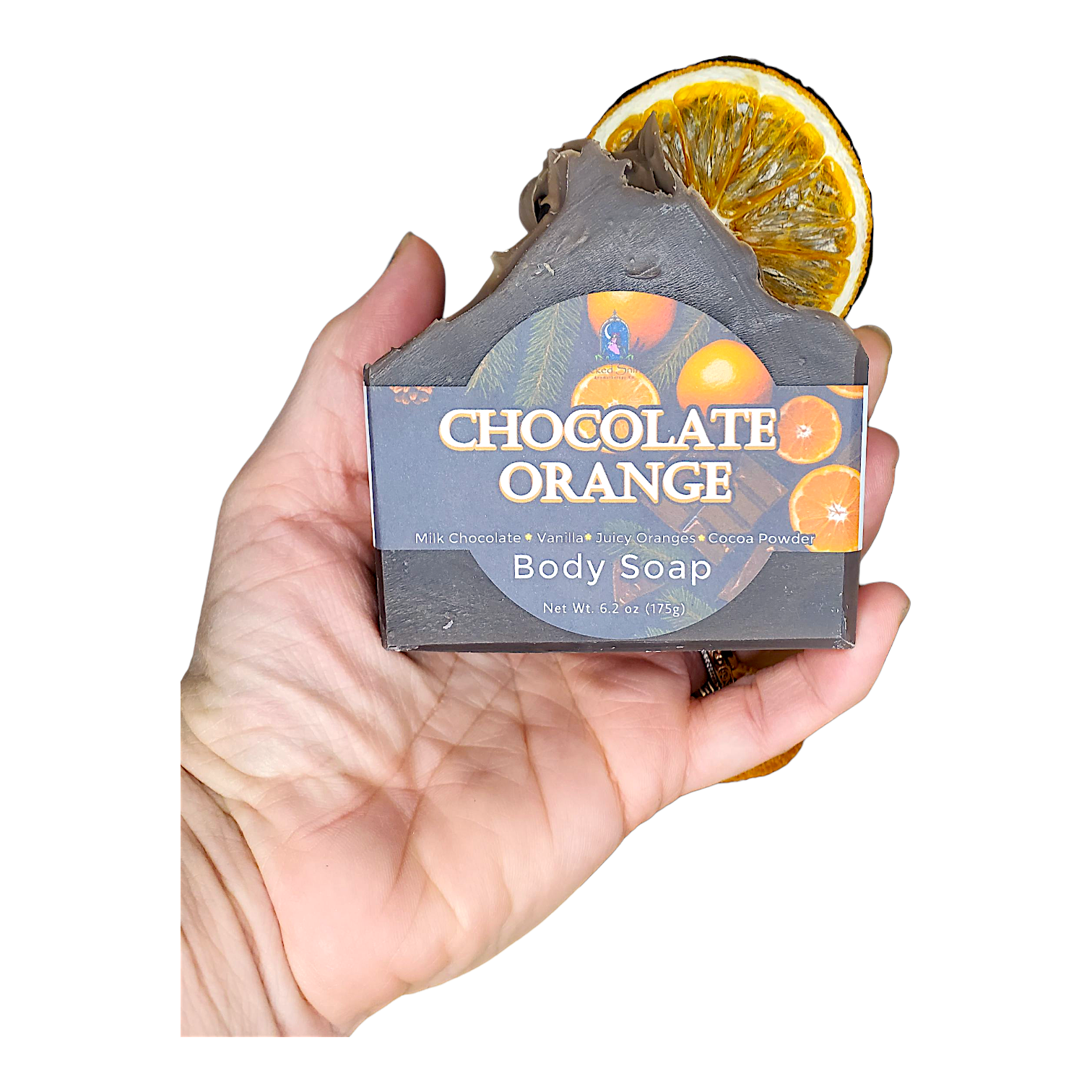 Hand holding a bar of chocolate orange body soap with a slice of orange on a white background