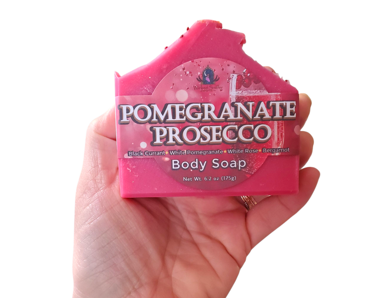 Pink bar of soap labeled 'Pomegranate Prosecco' held in a hand against a white background