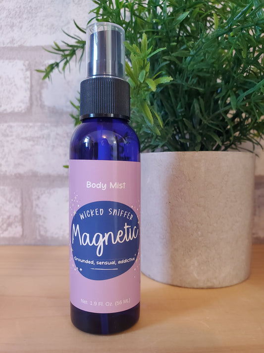 Blue spray bottle with a pink label on a textured surface with greenery in the background