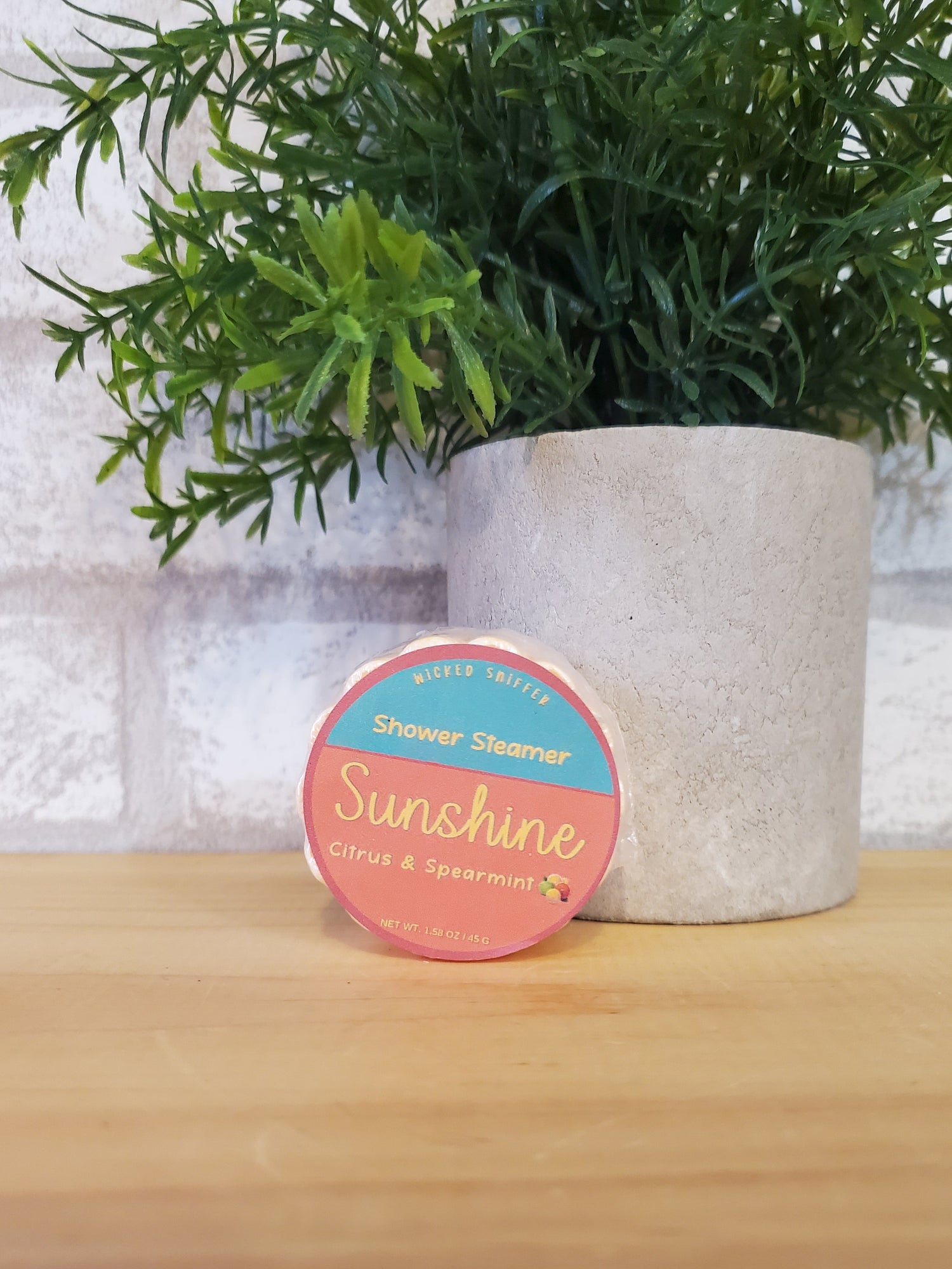 Sunshine shower steamer on a textured surface with greenery