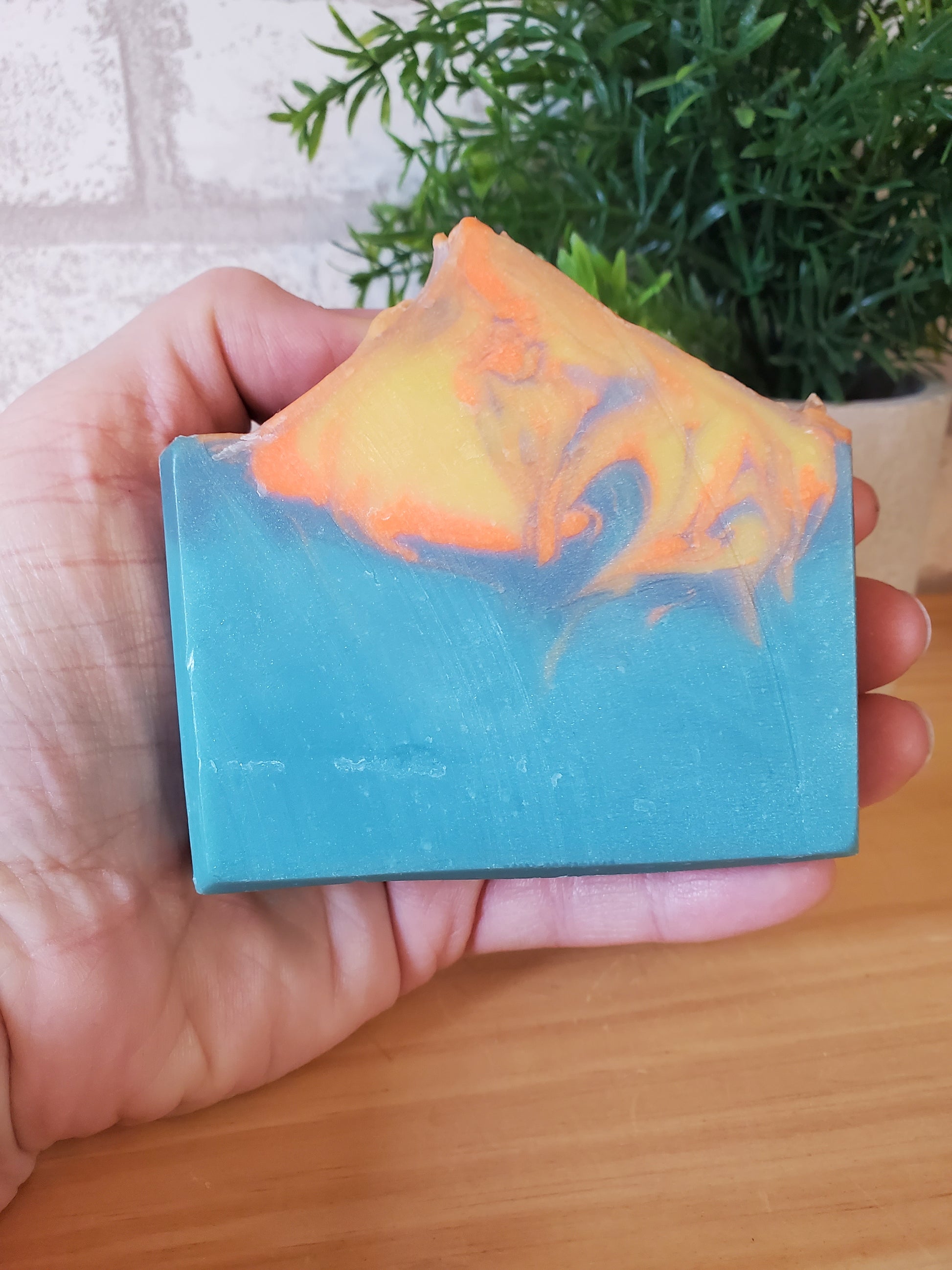 Hand holding a Bar of handmade, cold process soap  with 'Sunset' label, made in Vermont 