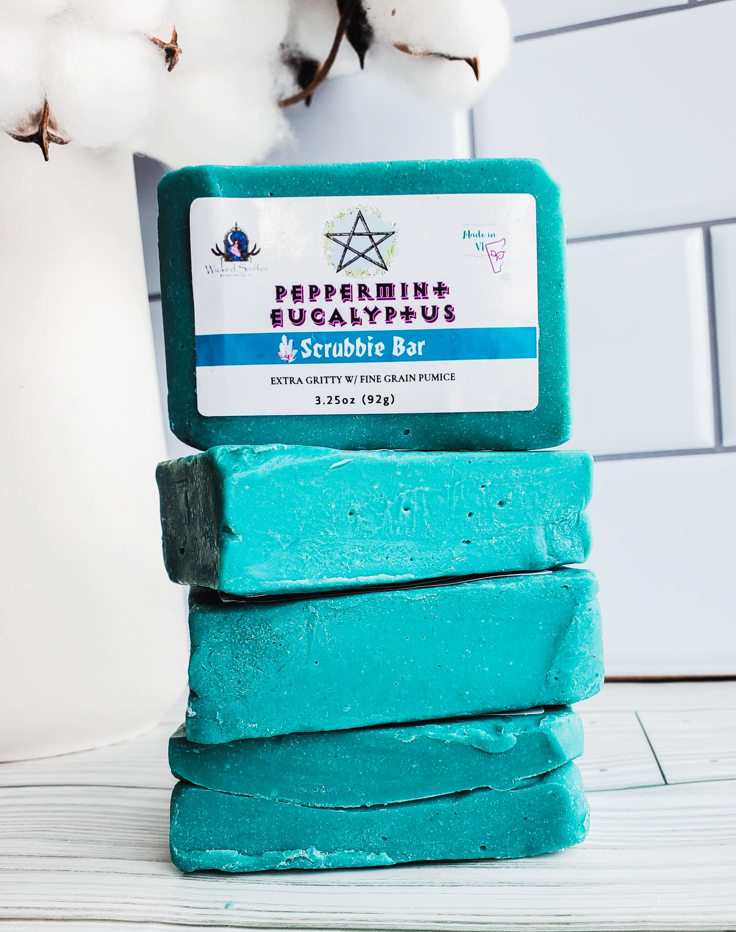 Picture of 4 blue bars of soap stacked high with a white rectangular label with a pentagram.