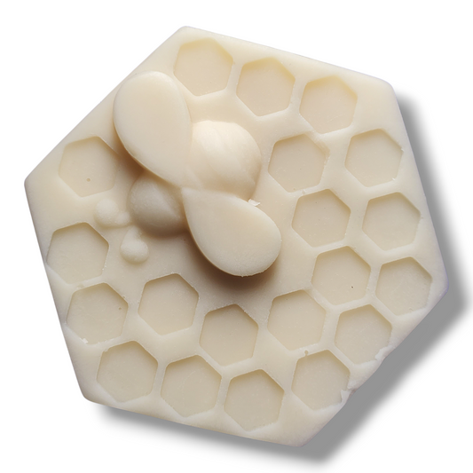 Hexagonal lotion bar with honeycomb pattern and honey droplets on a white background