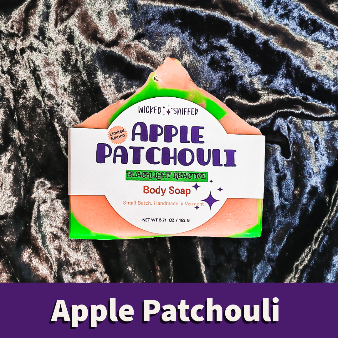 A body soap bar labeled 'Apple Patchouli' placed on a dark textured background with a purple banner at the bottom reading 'Apple Patchouli'.