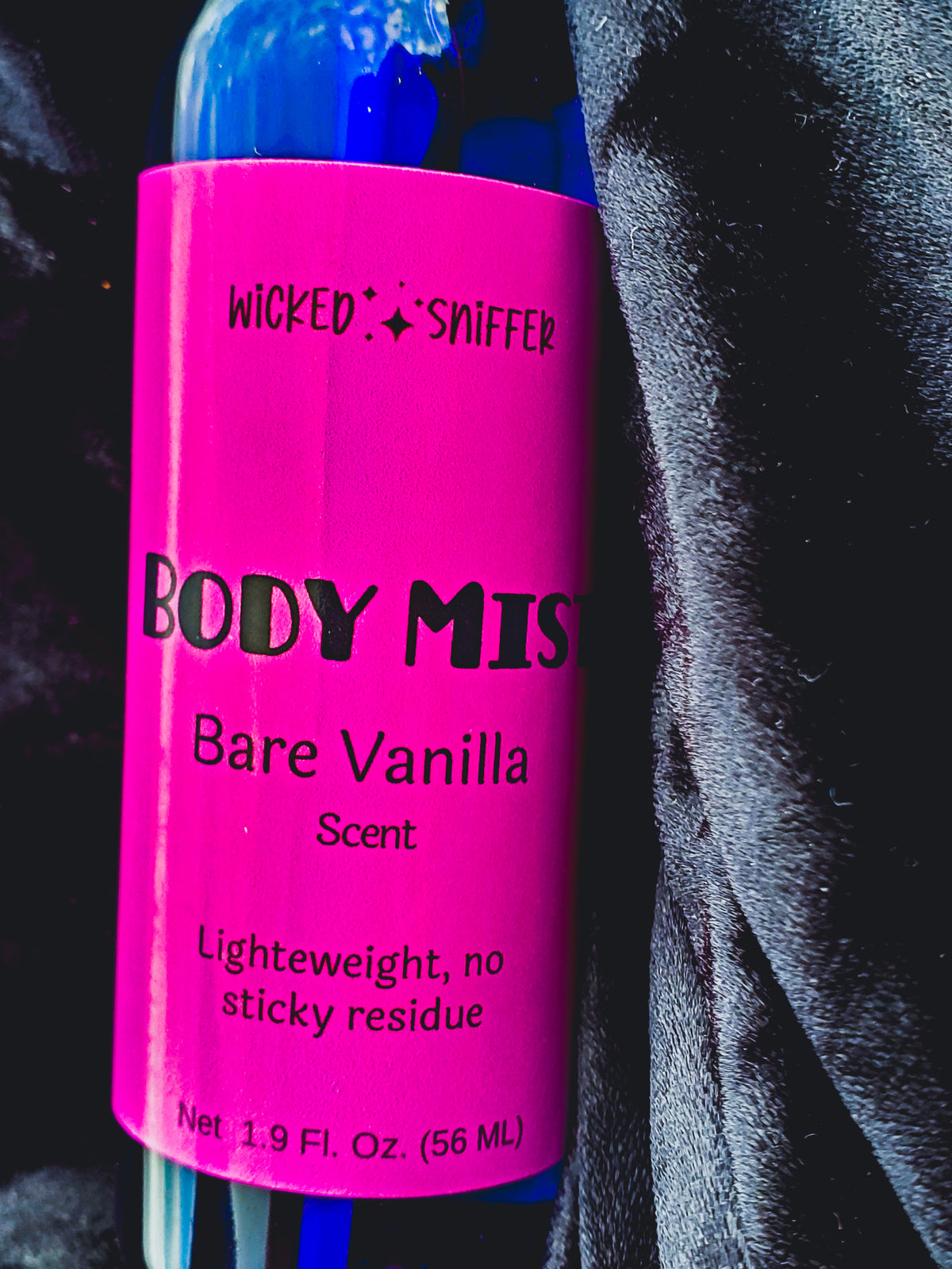 Body mist with pink label and blue top on a dark background