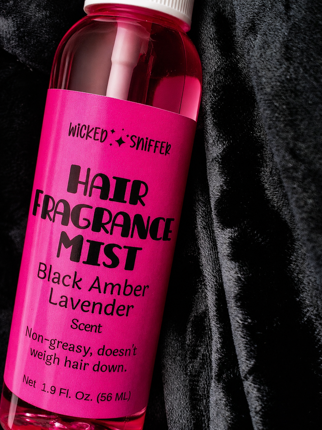 Pink bottle of hair fragrance mist with black text on a dark background