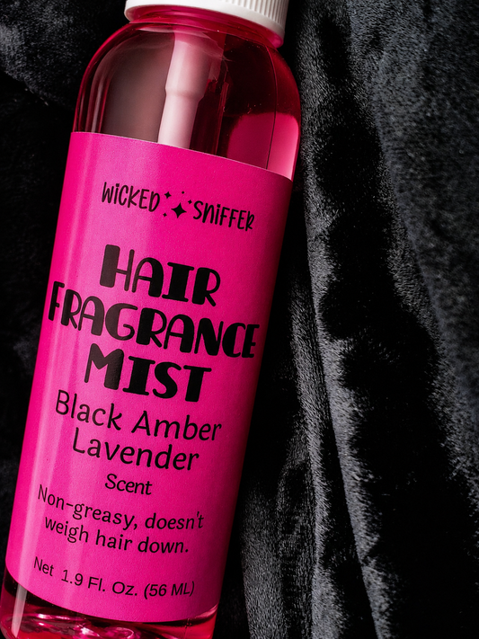 Pink bottle of hair fragrance mist with black text on a dark background