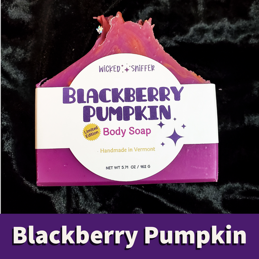 A bar of Wicked Sniffer Blackberry Pumpkin Body Soap, showing its magenta and purple top and a white label with purple text, set against a black velvet background with a purple banner at the bottom.