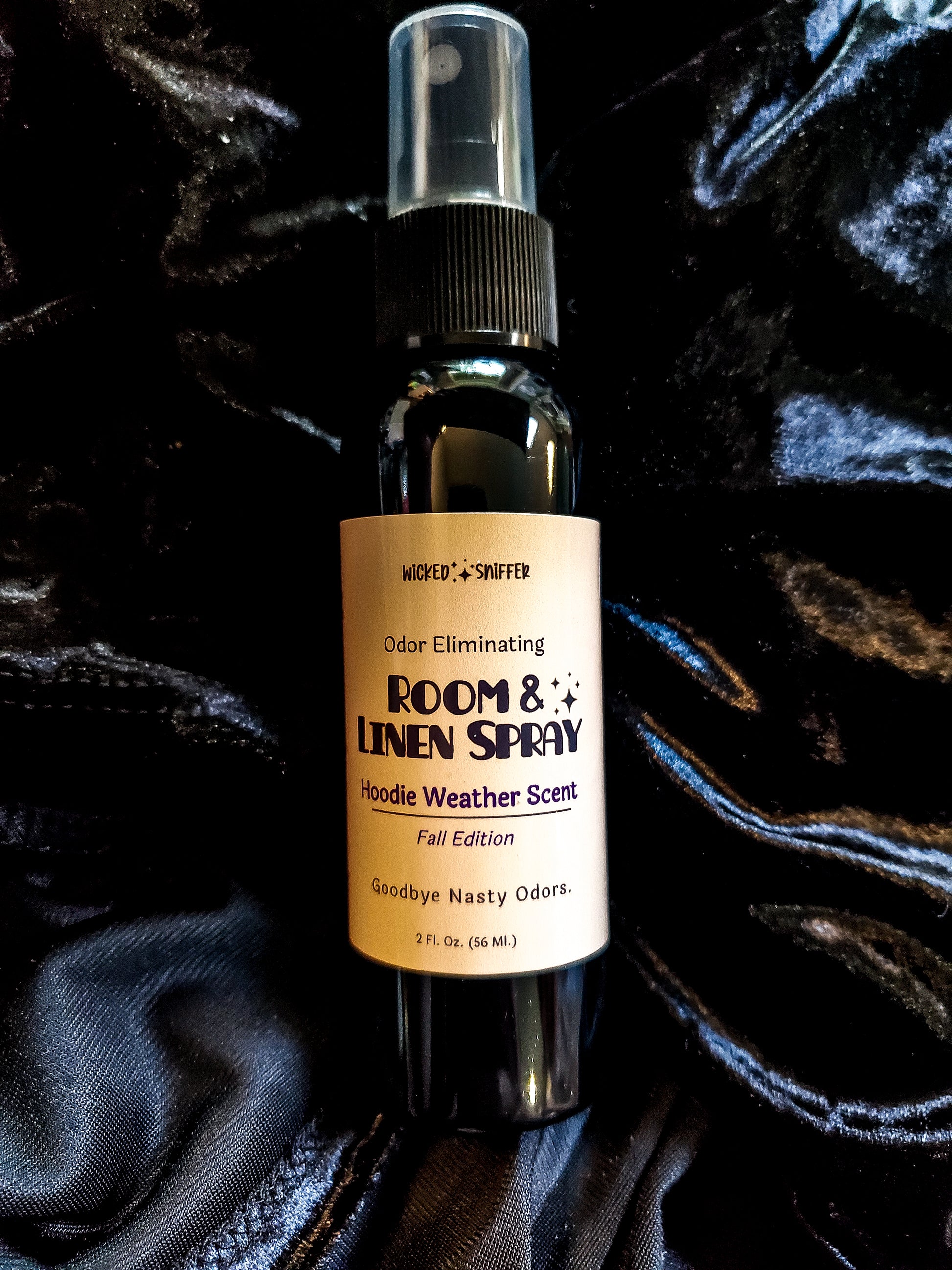 Black bottle with tan label that says Room & linen spray on a black background.