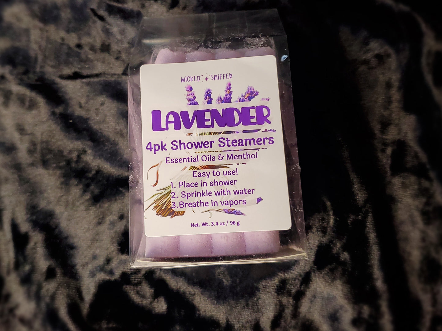 Pack of lavender shower steamers on a textured dark surface