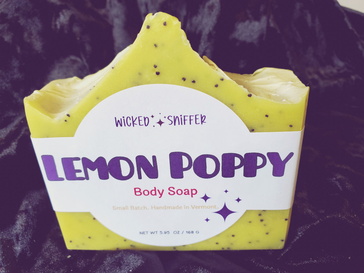 Bar of handmade Lemon Poppy yellow cold process soap  on a dark background made in Vermont 