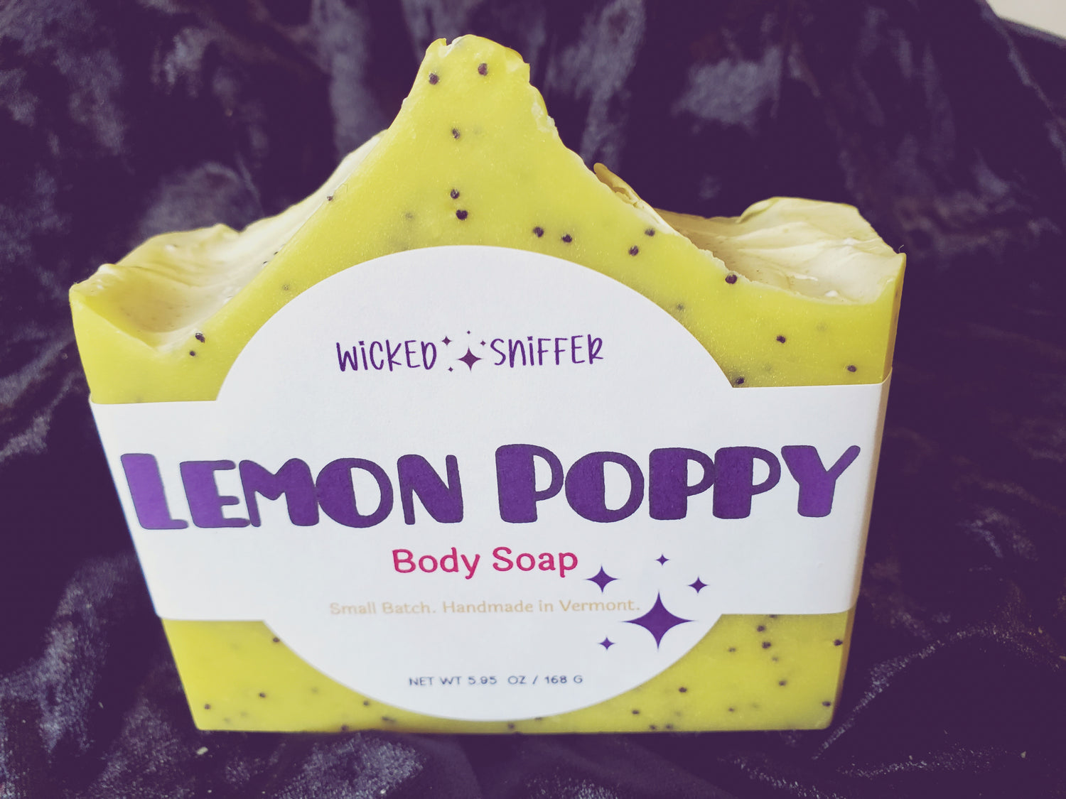 Bar of handmade Lemon Poppy yellow cold process soap  on a dark background made in Vermont 