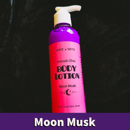A bottle of Wicked Sniffer Avocado Shea Body Lotion in the Moon Musk scent, featuring a bright pink label and a purple cap, set against a dark textured background with a purple banner at the bottom.