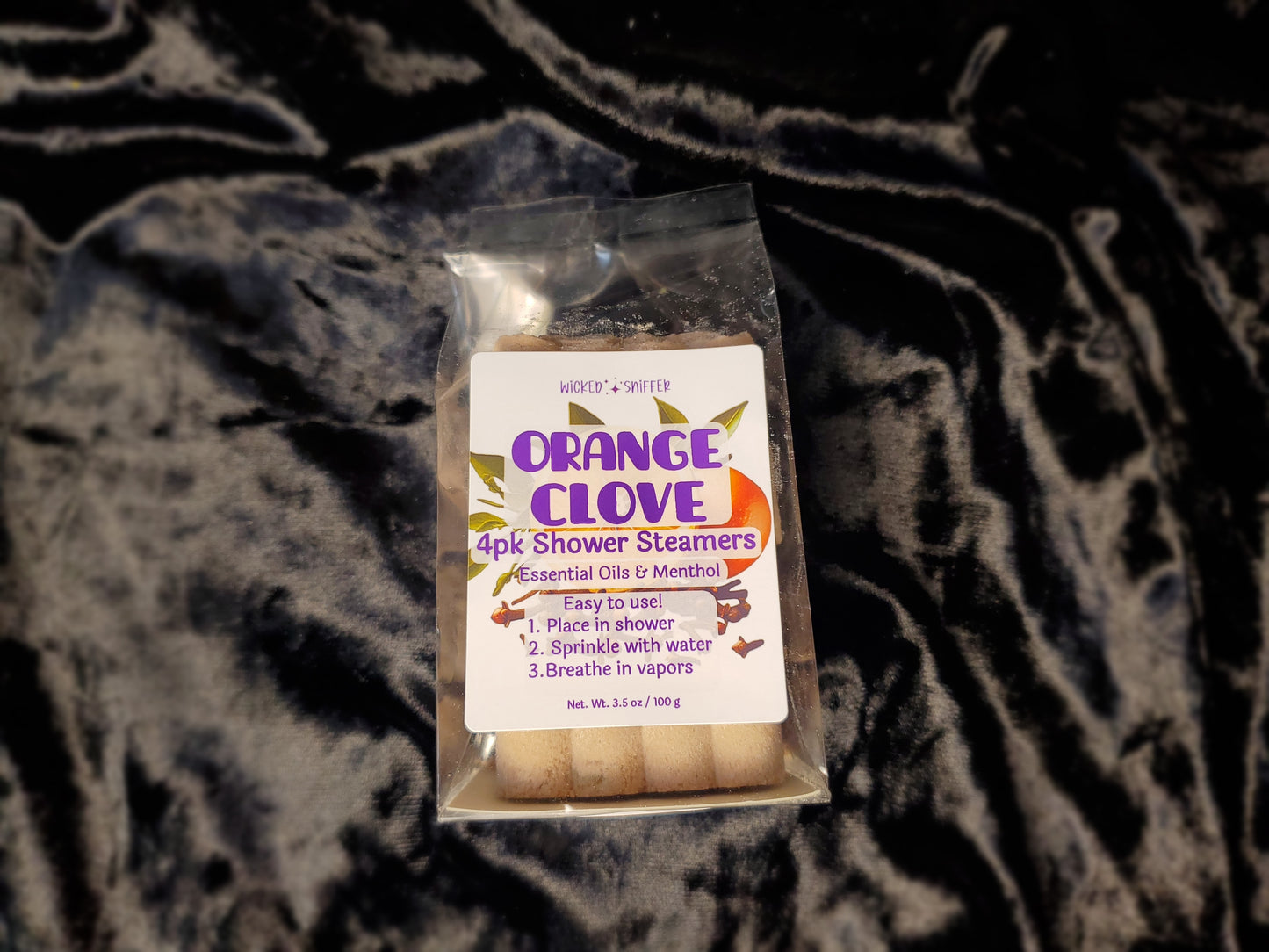 Pack of Orange Clove shower steamers on a dark textured background