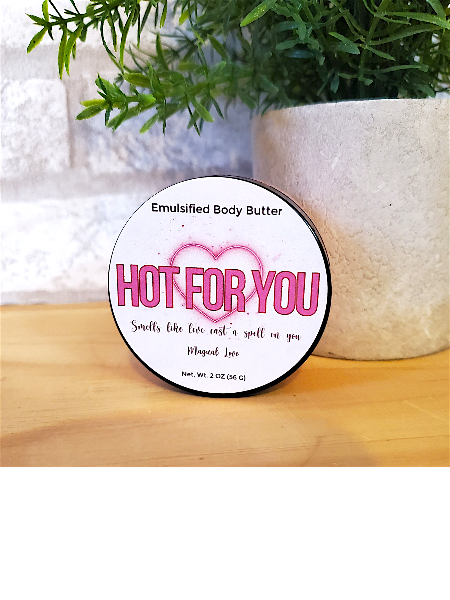 Body butter container labeled 'Hot for You' on a wooden surface with a plant in the background