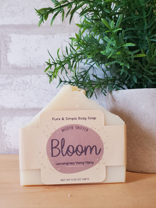 Bar of soap with 'Bloom' branding on a white surface with greenery