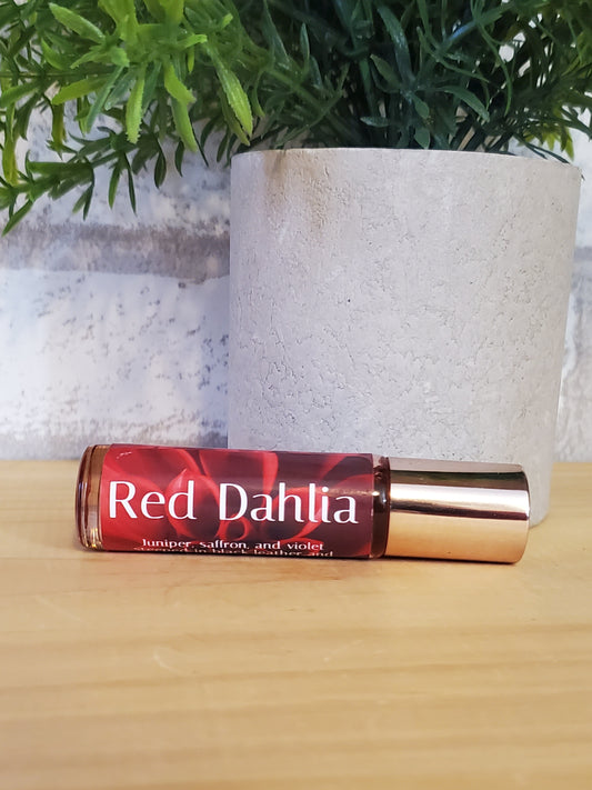 Red Dahlia perfume bottle on a textured surface with greenery