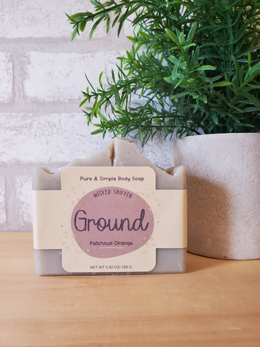 Bar of soap with a label on a white surface next to greenery