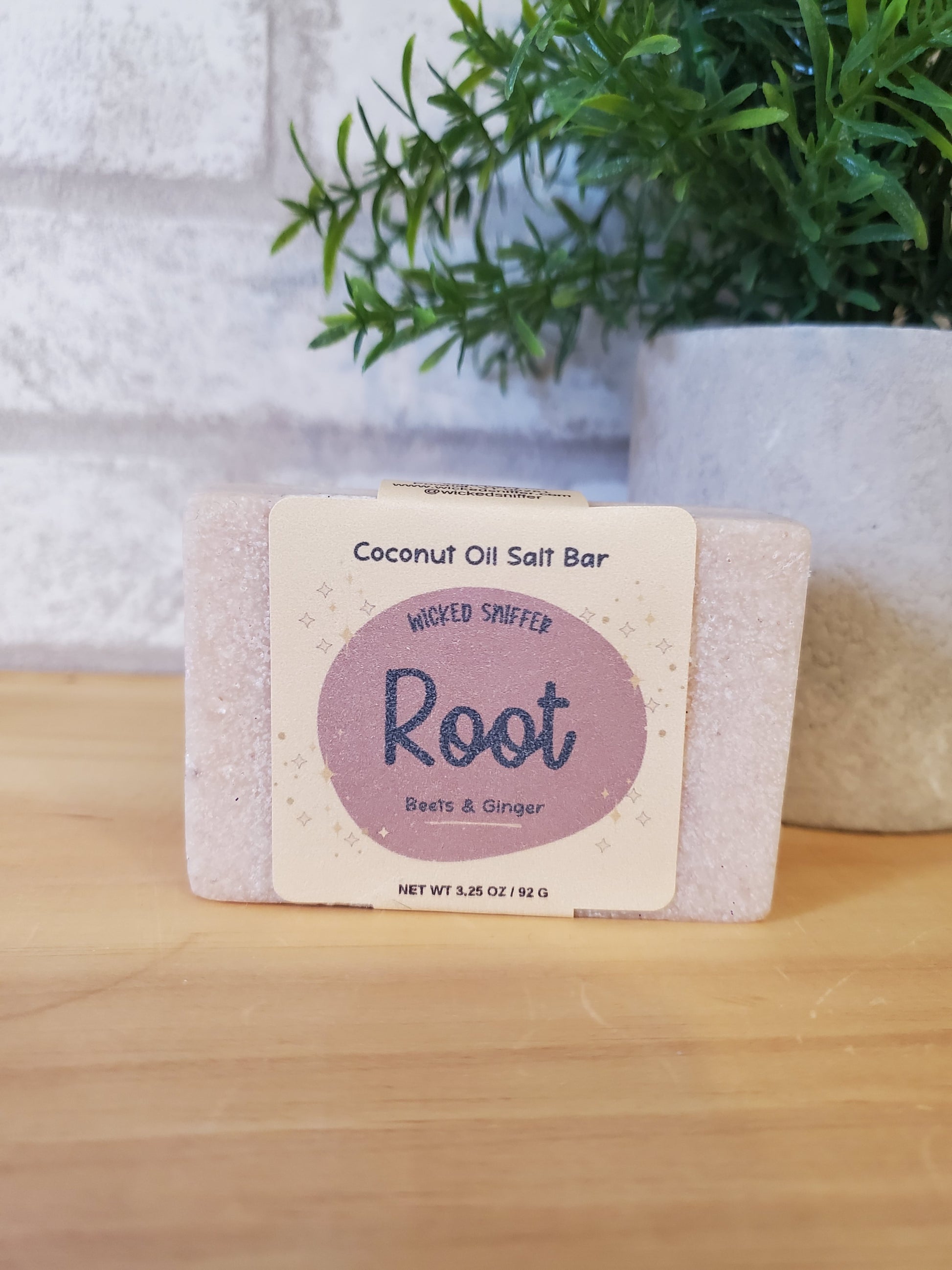 Bar of soap with a label on a wooden surface next to greenery