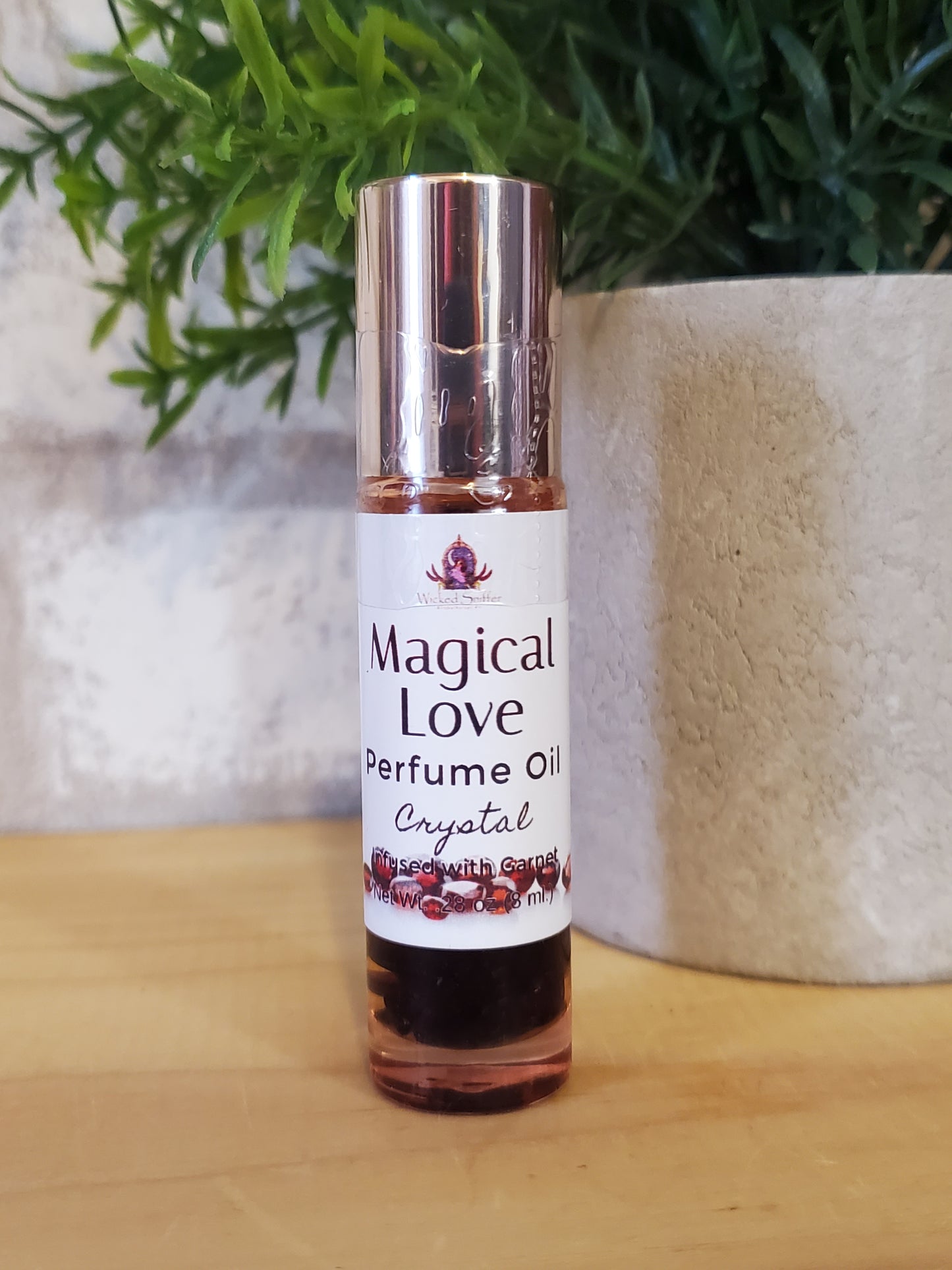 Roll-on perfume bottle labeled 'Magical Love' on a textured surface with greenery.