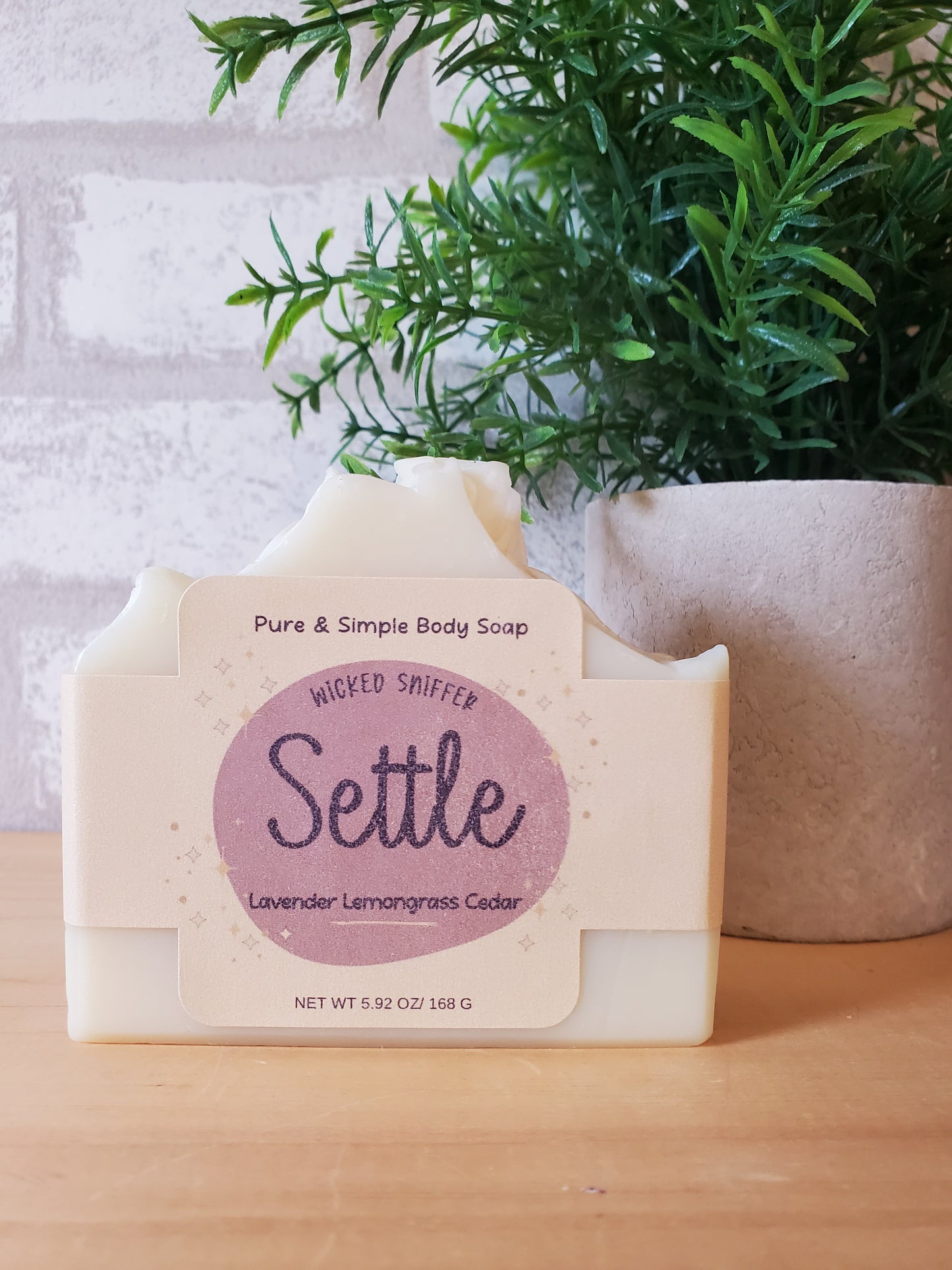 Bar of soap with a 'Settle' label on a white surface with greenery
