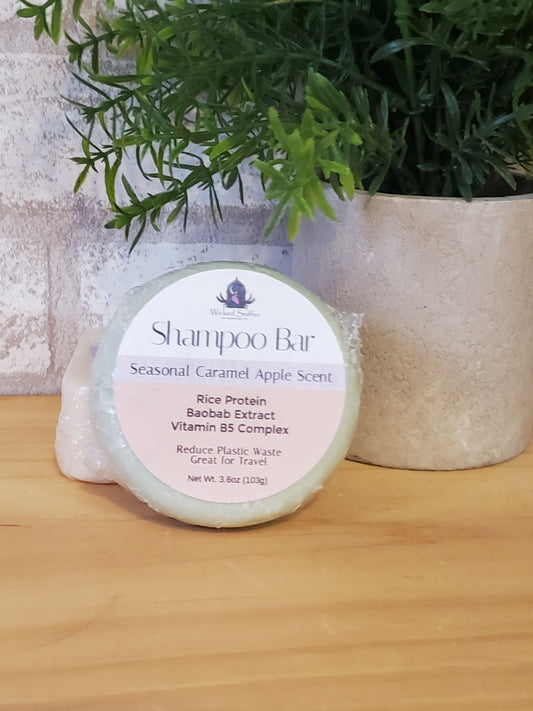 Shampoo bar with a label on a wooden surface next to greenery