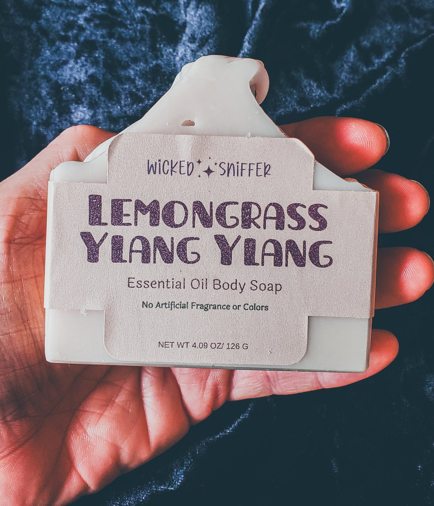 Hand holding tan soap on a black background