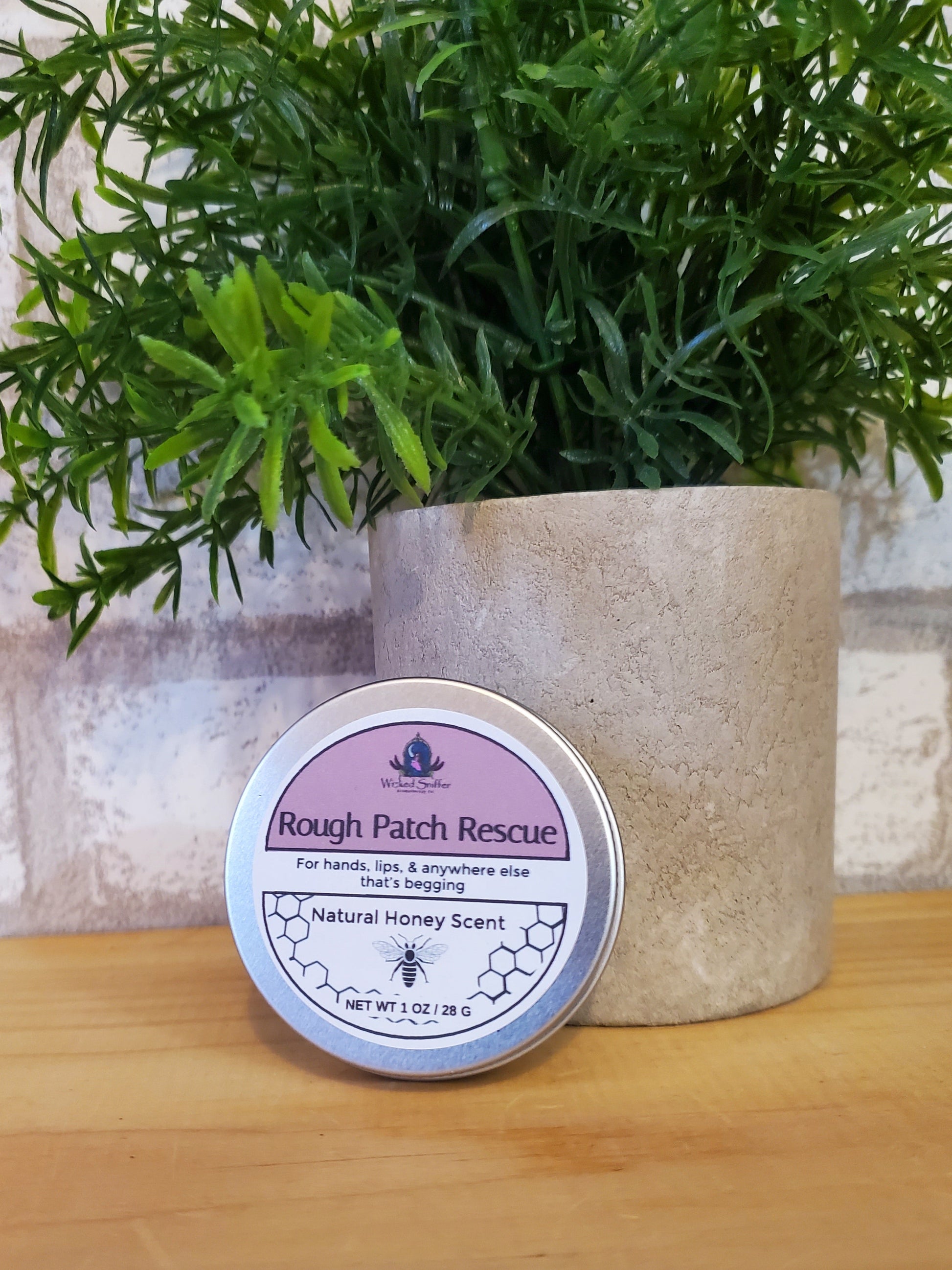 Tin of Rough Patch Rescue on a wooden surface with greenery
