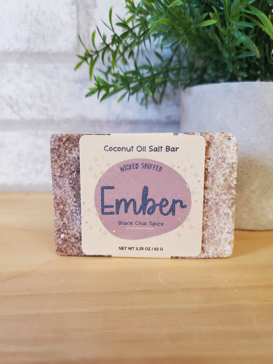 Coconut oil salt bar with 'Ember' branding on a wooden surface with greenery.