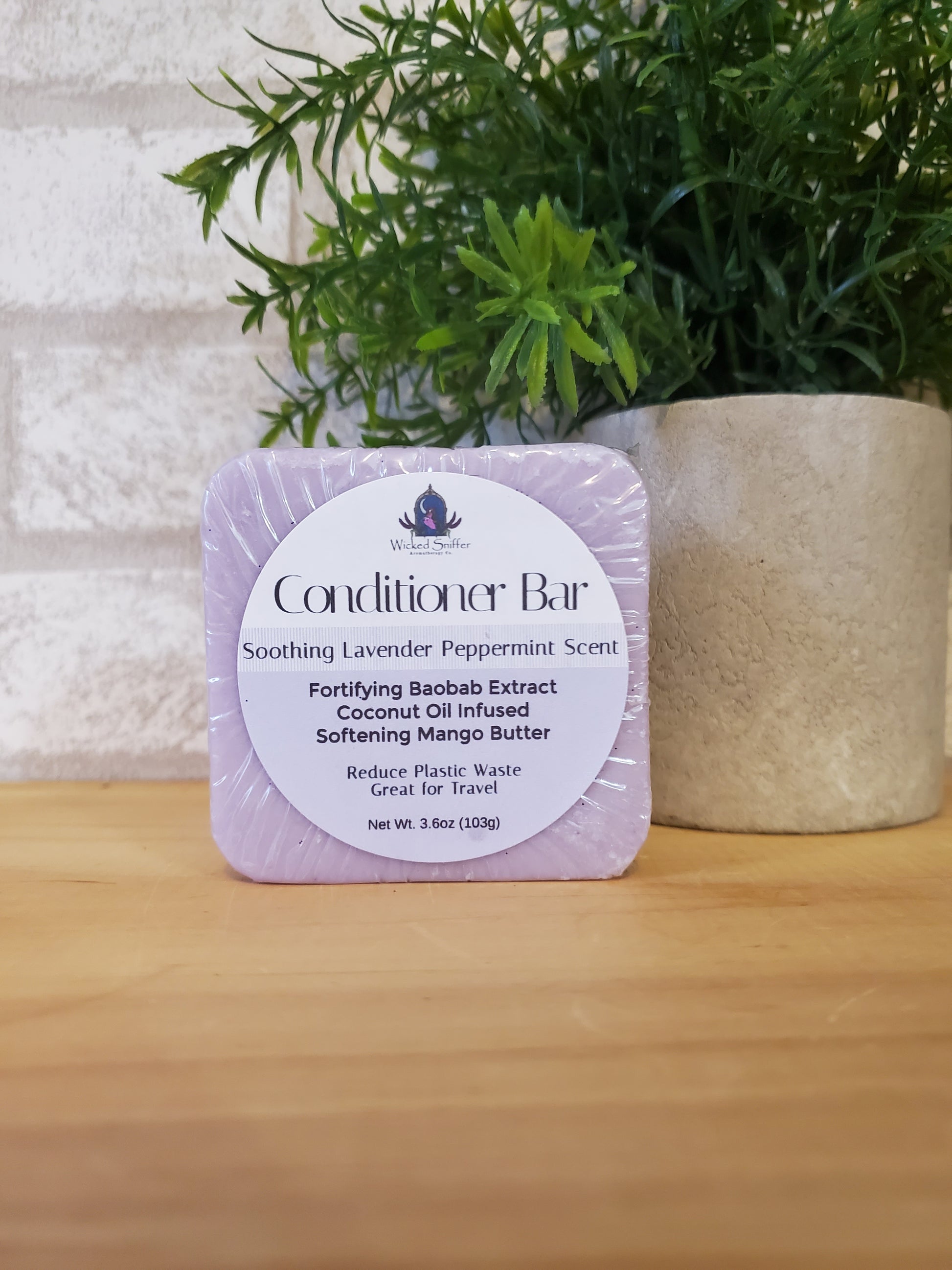 Bar of conditioner with a label on a wooden surface next to greenery