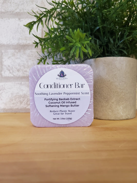 Bar of conditioner with a label on a wooden surface next to greenery