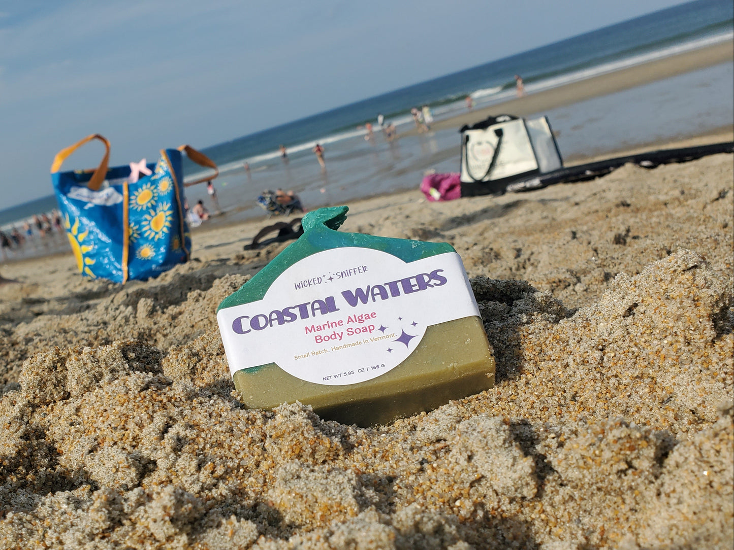 A bar of Coastal Waters Marine Algae Soap resting in the sand on a beach