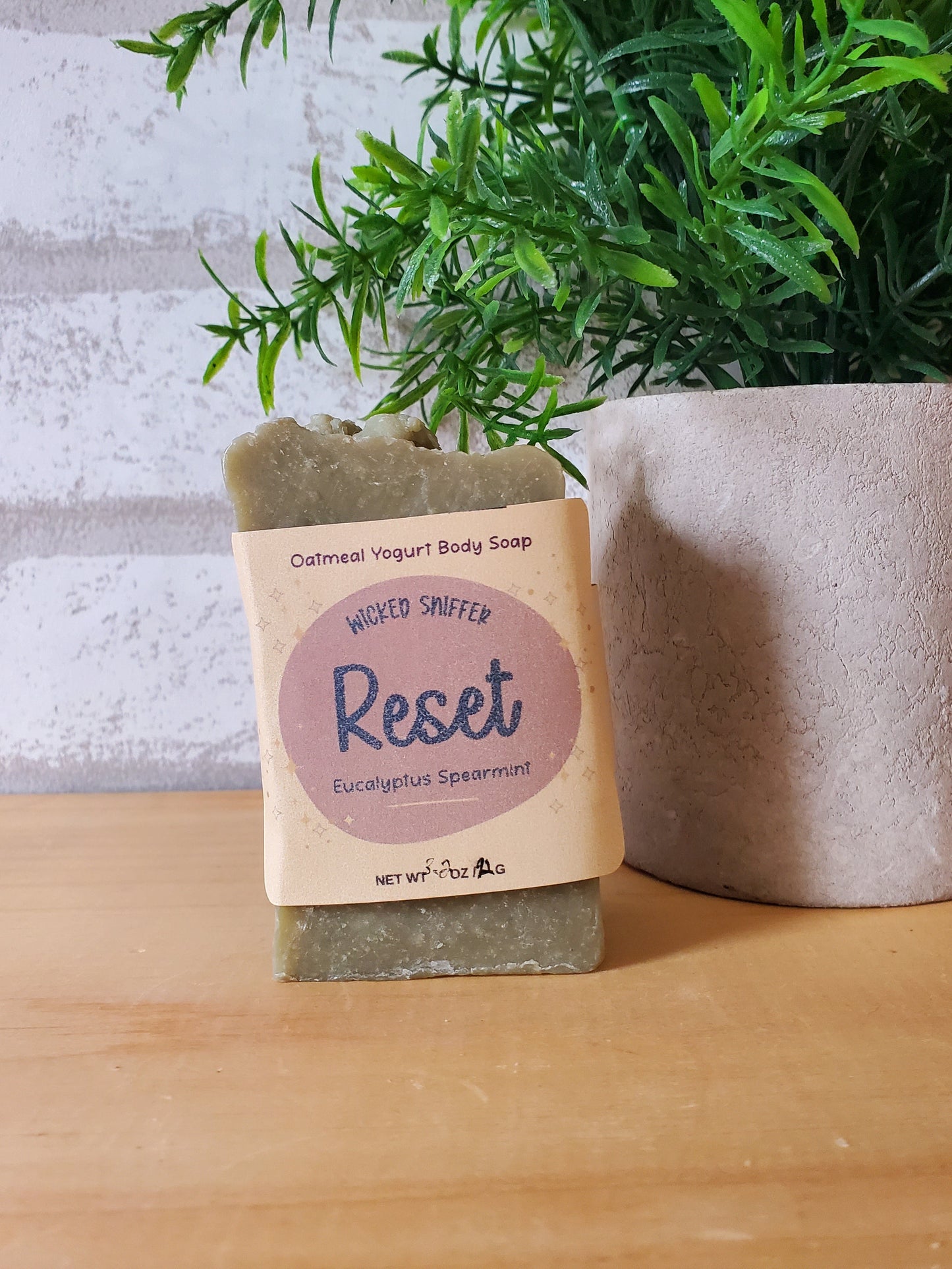 Bar of soap with 'Reset' label next to a plant on a wooden surface