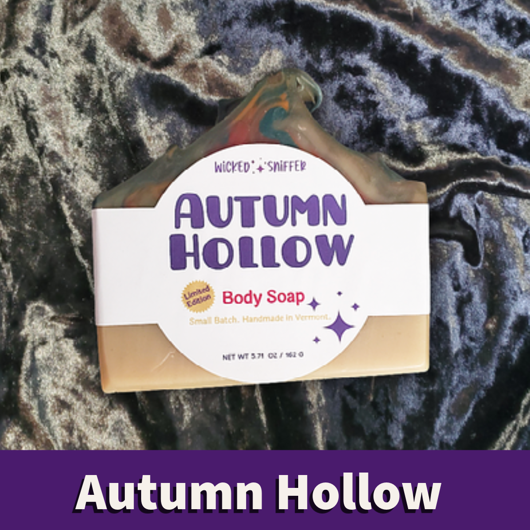 A bar of 'Autumn Hollow' body soap with a white paper label, displayed on a dark, textured velvet fabric background with a purple banner at the bottom.