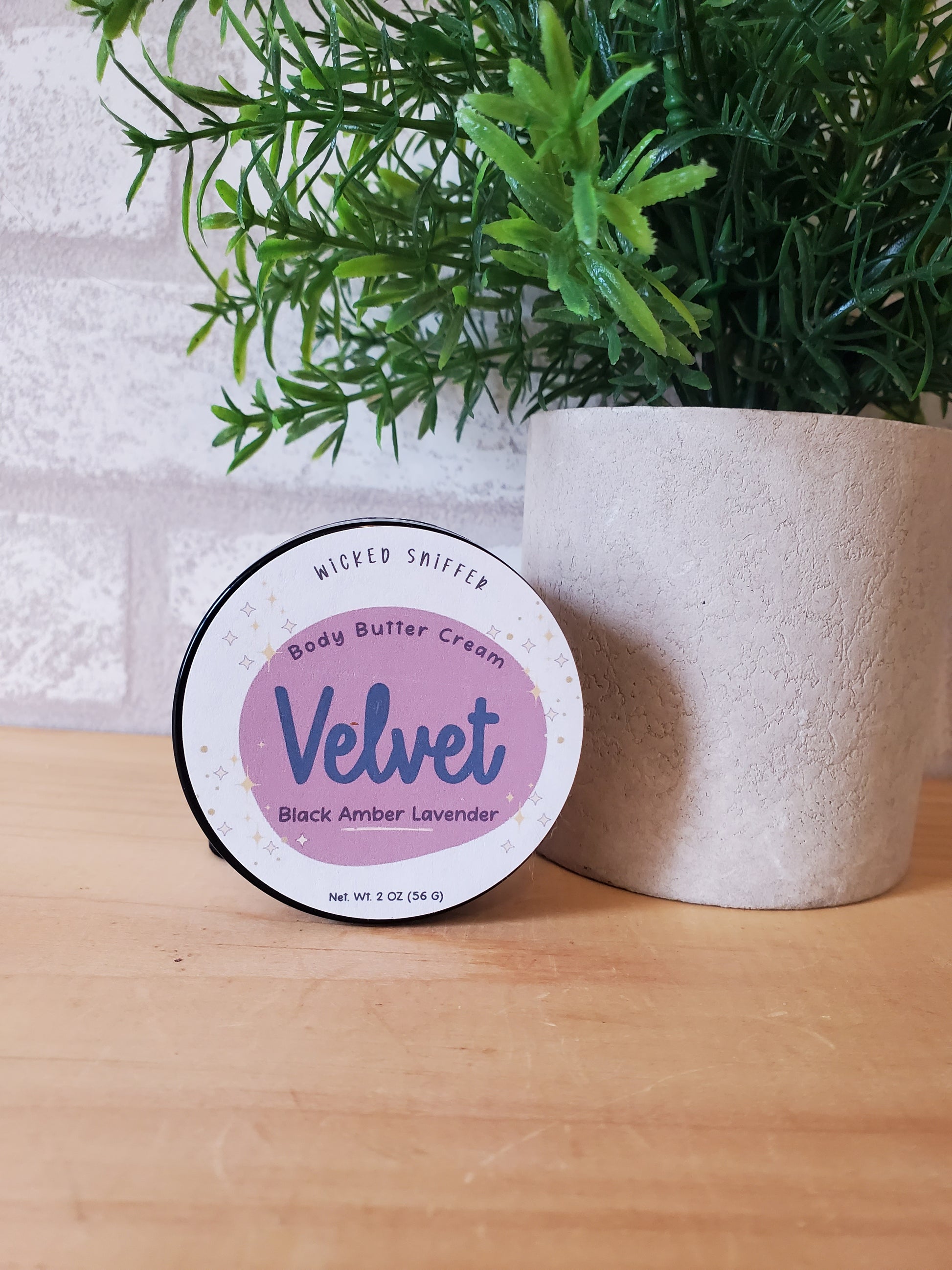 Jar of Velvet body butter cream on a wooden surface with greenery