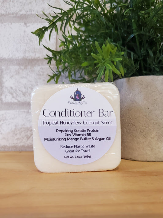 Bar of conditioner with a label on a wooden surface next to greenery