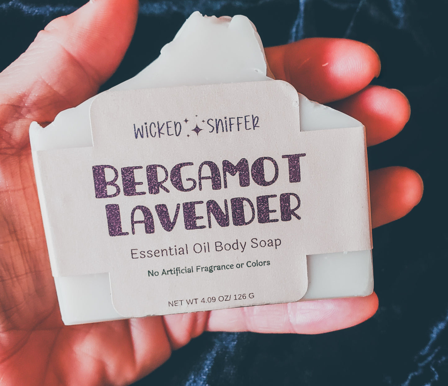 Hand holding a tan bar of soap on a black background